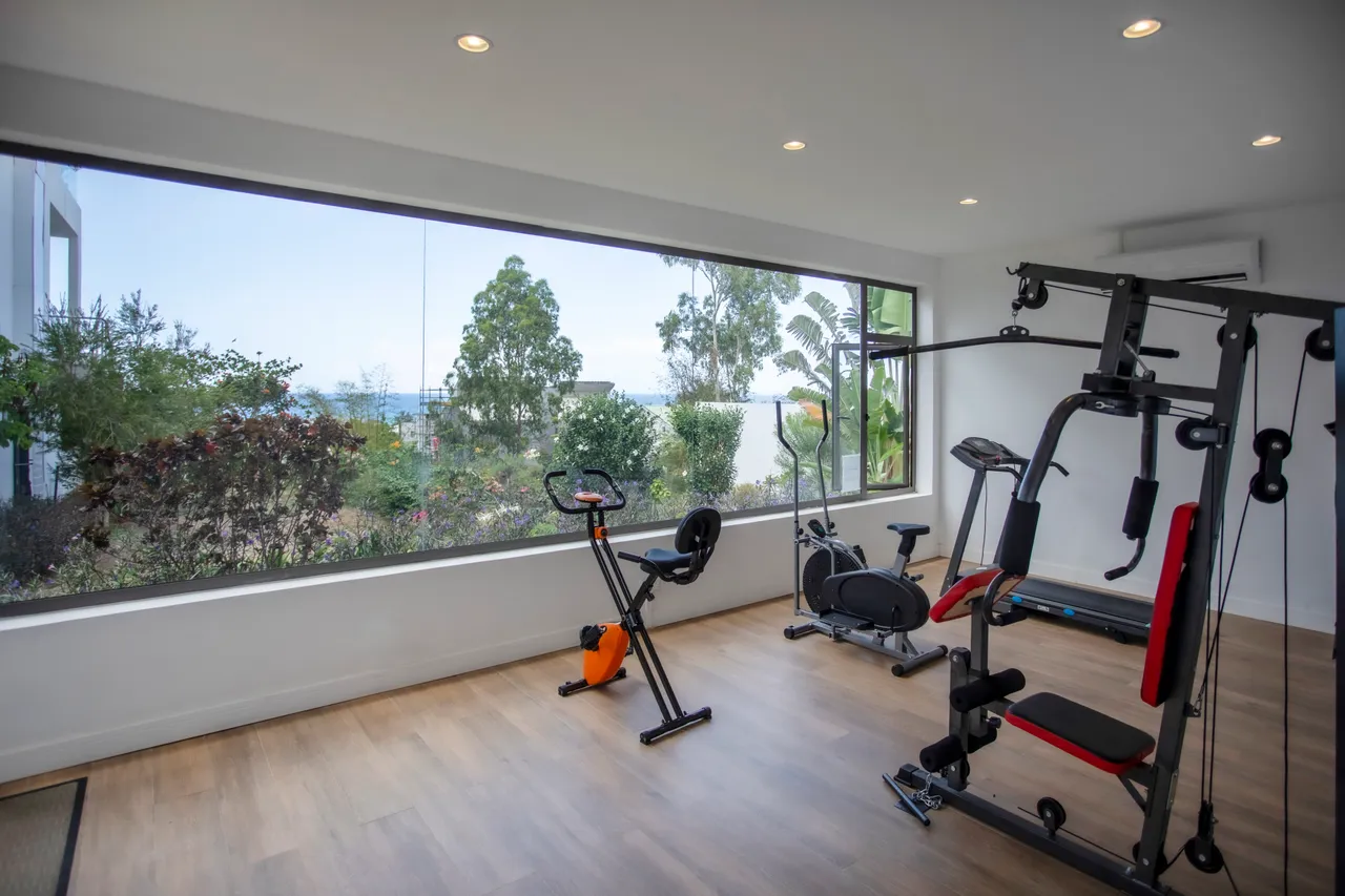 Salle de sport avec vue sur la mer. Équipements variés pour l'exercice.