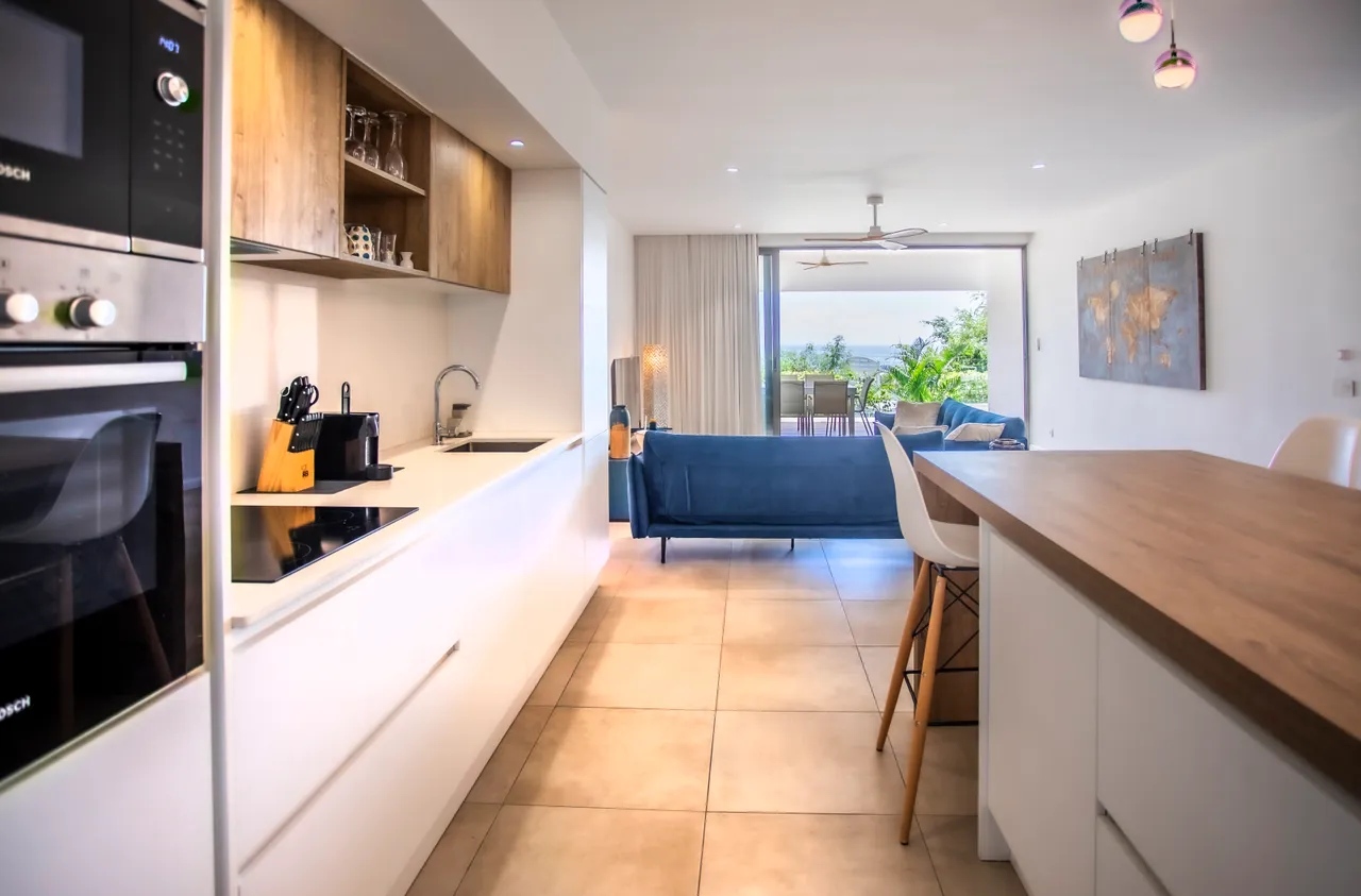 Espace de vie lumineux avec cuisine ouverte et vue sur la mer. Mobilier moderne et accueillant.