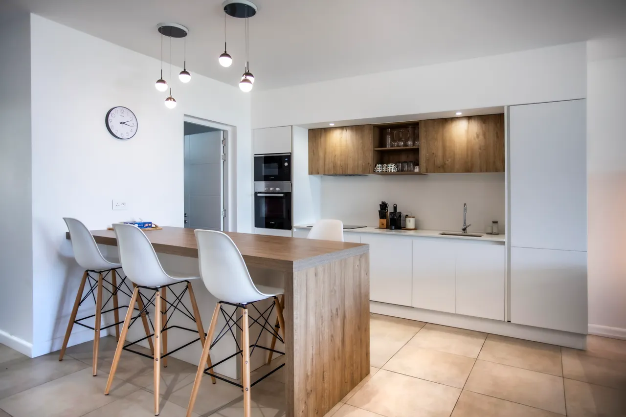 Plan de travail en bois avec bar et chaises blanches. Espace moderne et fonctionnel.