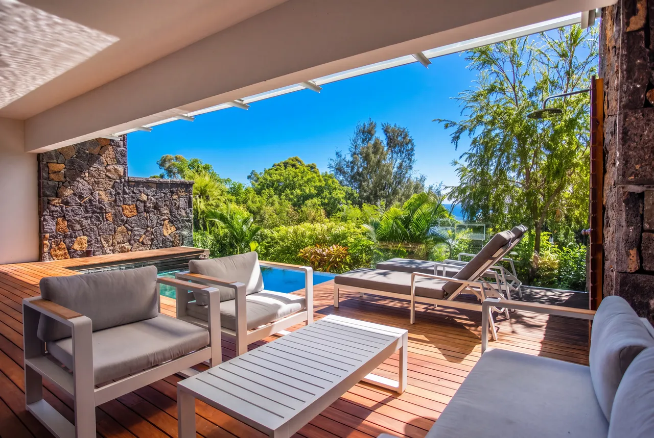 Tons naturels et bois au sol. Espace extérieur avec mobilier contemporain et vue sur la verdure.