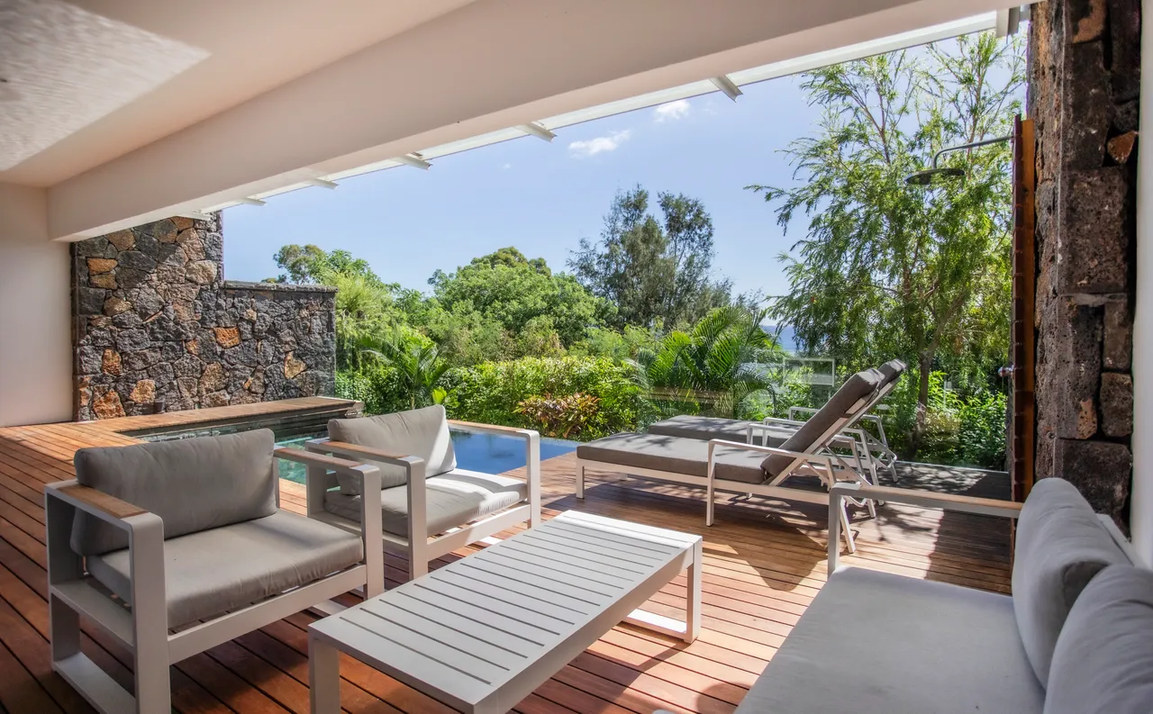 Tons naturels et bois au sol. Espace extérieur avec mobilier contemporain et vue sur la verdure.