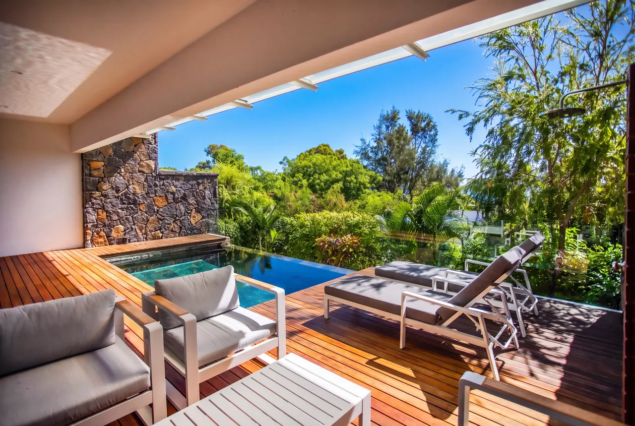 Espace extérieur avec mobilier en teck, vue sur la piscine et le jardin. Piscine à débordement accessible depuis le salon.