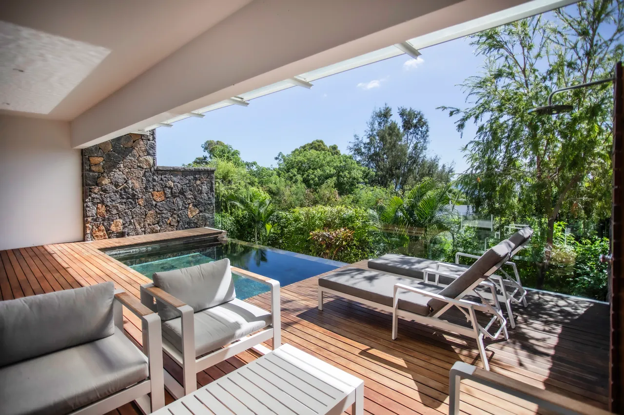 Espace extérieur avec mobilier en teck, vue sur la piscine et le jardin. Piscine à débordement accessible depuis le salon.