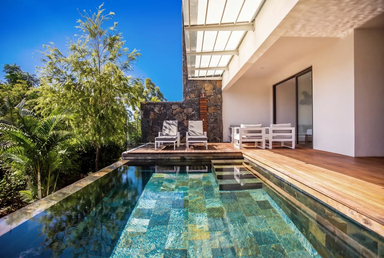 Espace extérieur avec chaises longues blanches, donnant sur la piscine. Vue sur la mer.