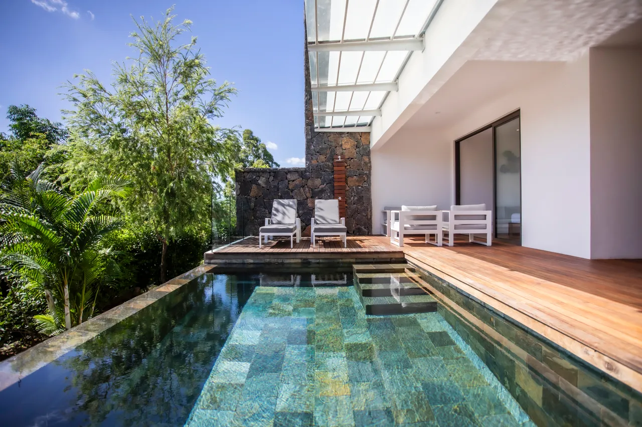 Espace extérieur avec chaises longues blanches, donnant sur la piscine. Vue sur la mer.