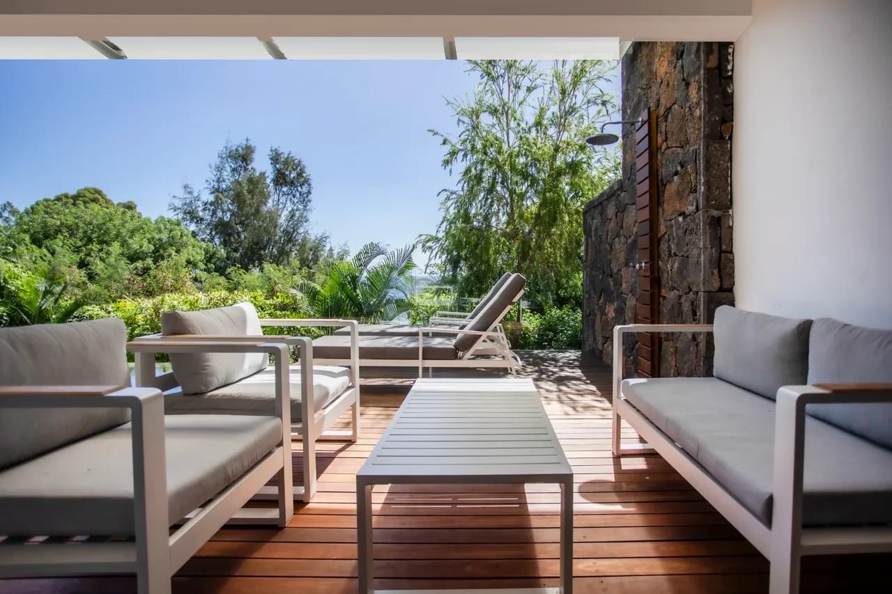 Coin salon extérieur avec mobilier moderne, vue dégagée sur la verdure.