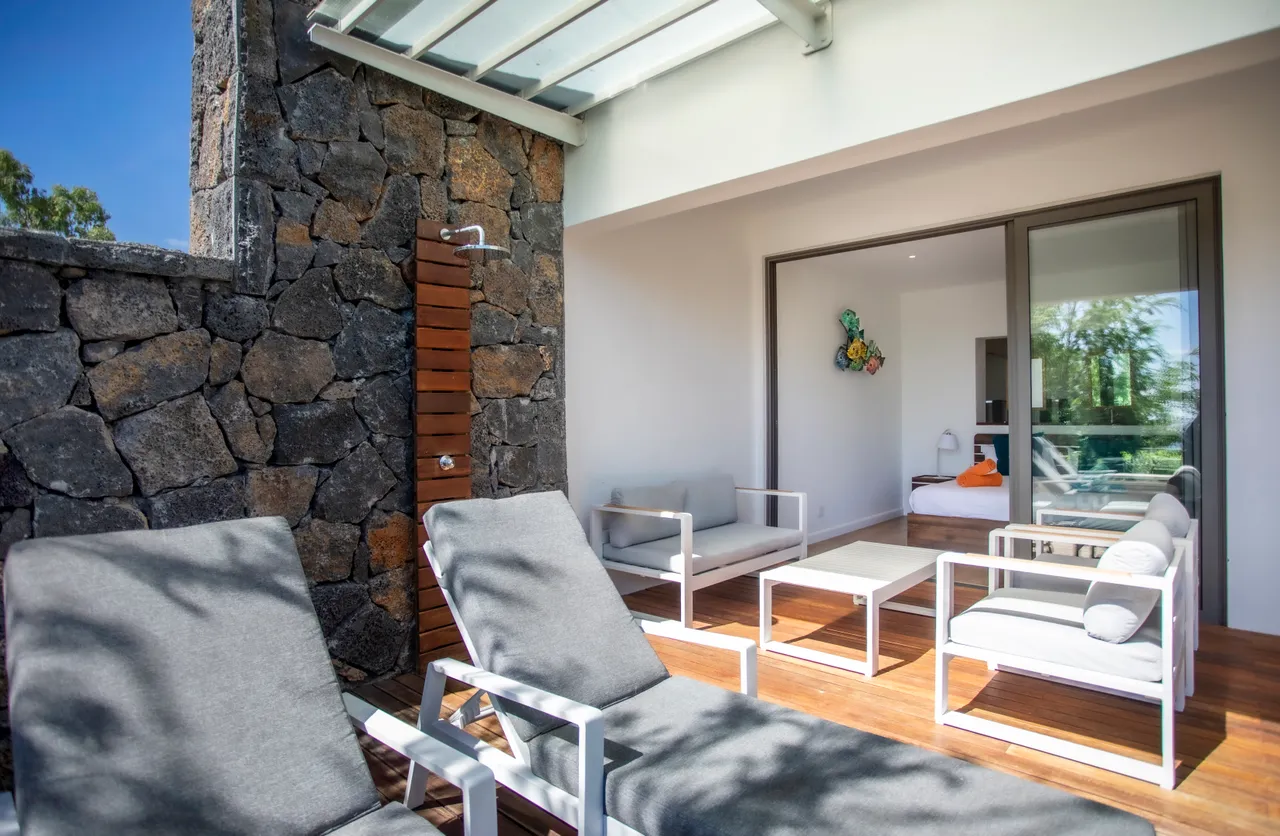 Tons gris et mobilier en teck sur la terrasse. Vue sur la mer depuis le salon.