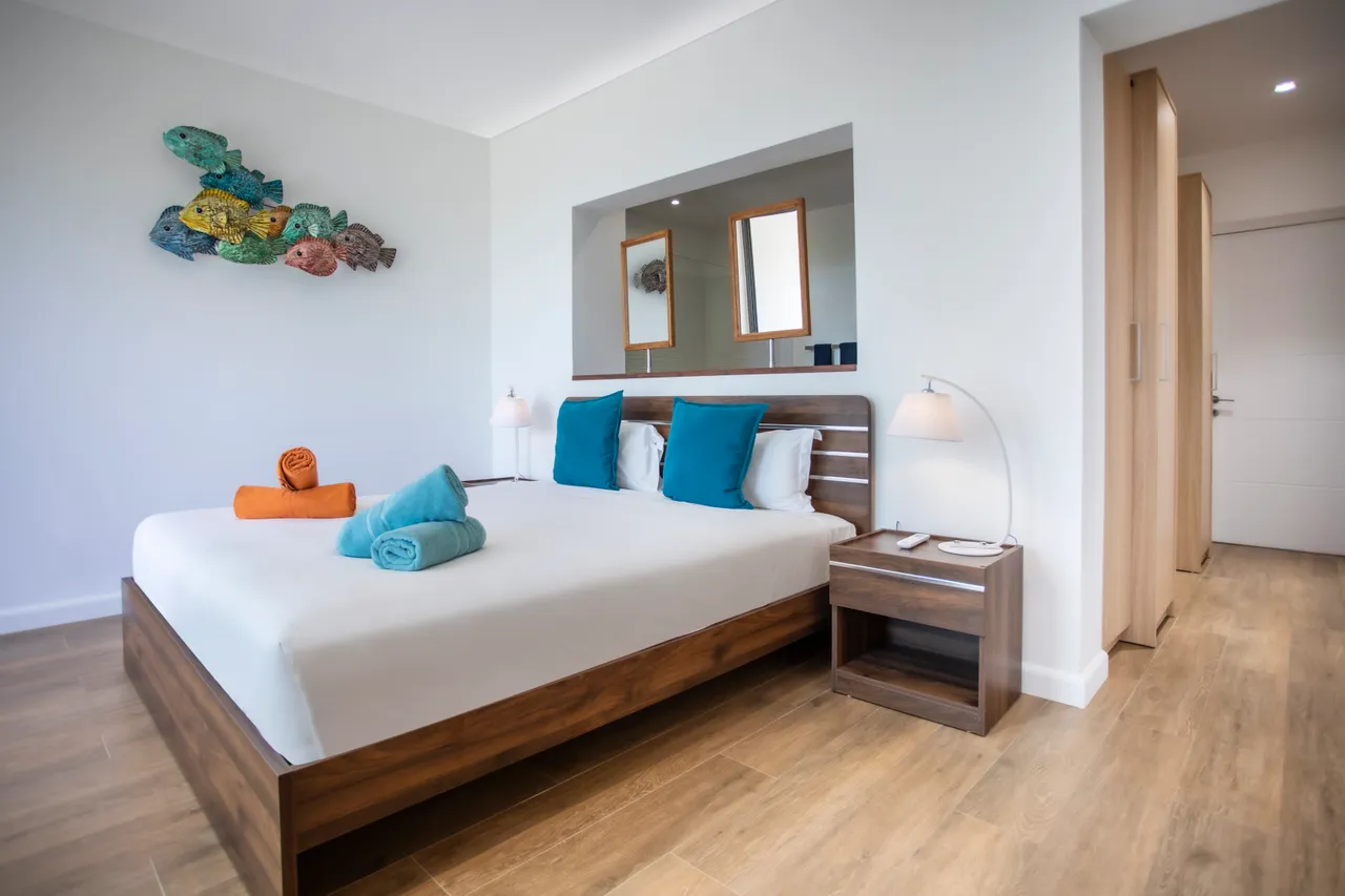 Chambre au parquet clair, équipée d'un lit double et d'un coin bureau. Décoration simple avec des touches de couleur.