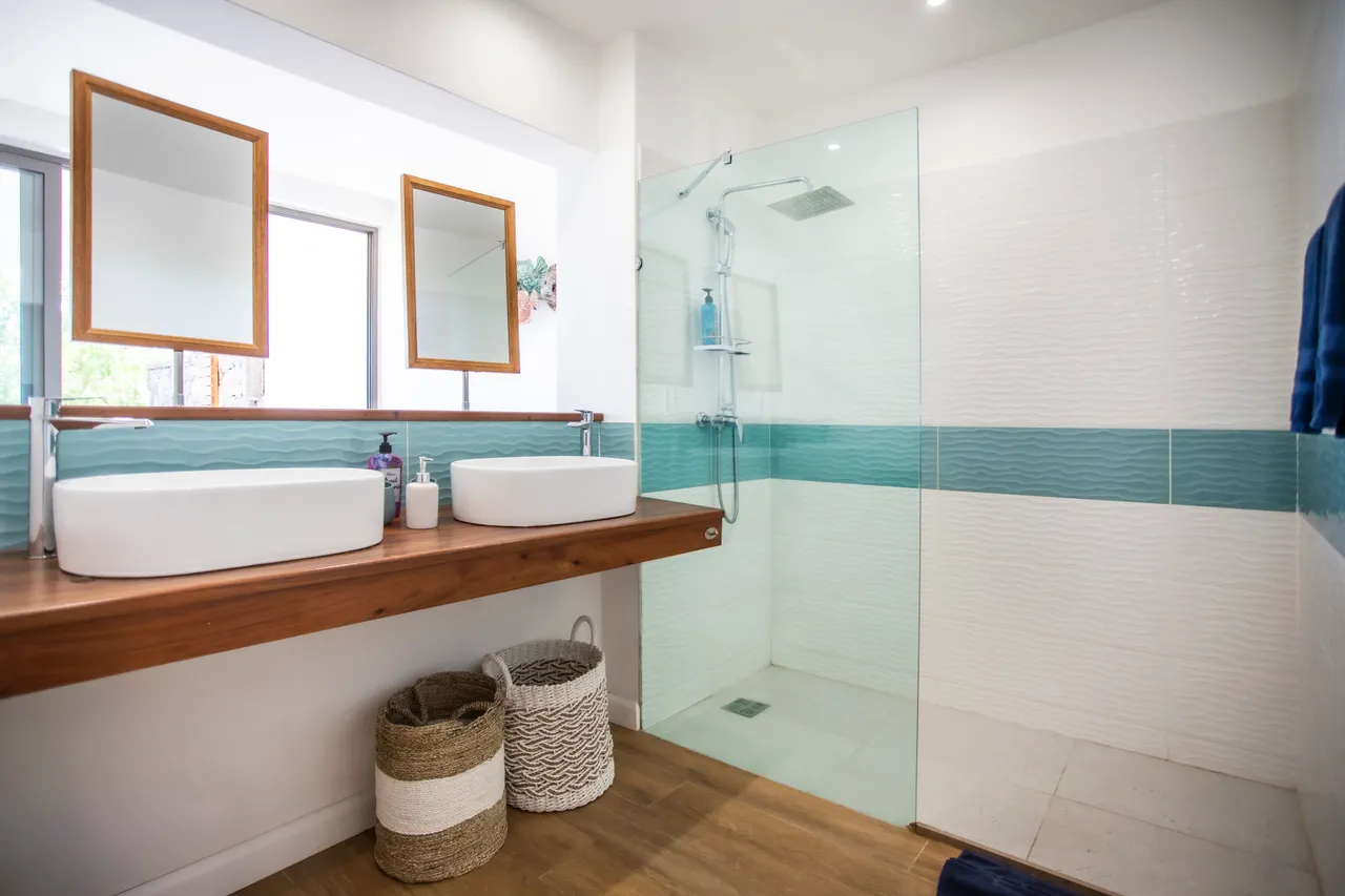 Salle de bain avec double vasque sur meuble en bois. Douches modernes et éclairage naturel.