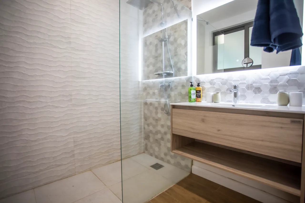 Salle de bain moderne avec douche spacieuse et éclairage LED. Étagères en bois pratique.