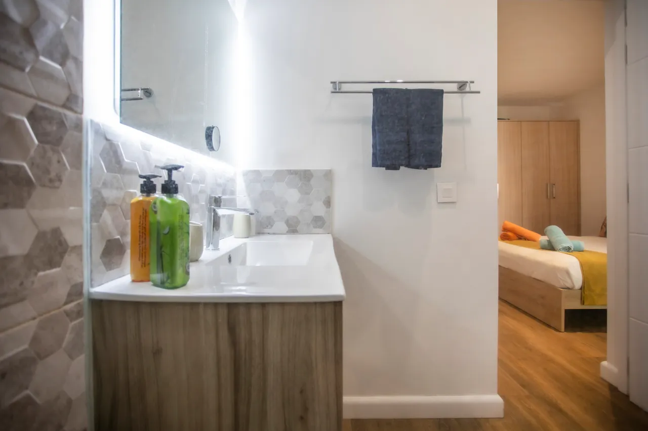 Murs en hexagones et meuble en bois clair. Évier spacieux avec rangements pratiques.