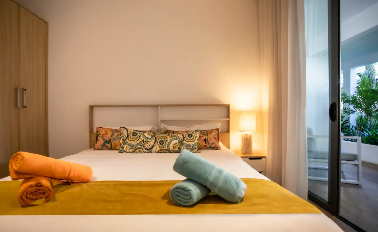 Chambre avec lit double et linge de lit coloré. Accès à un espace extérieur.