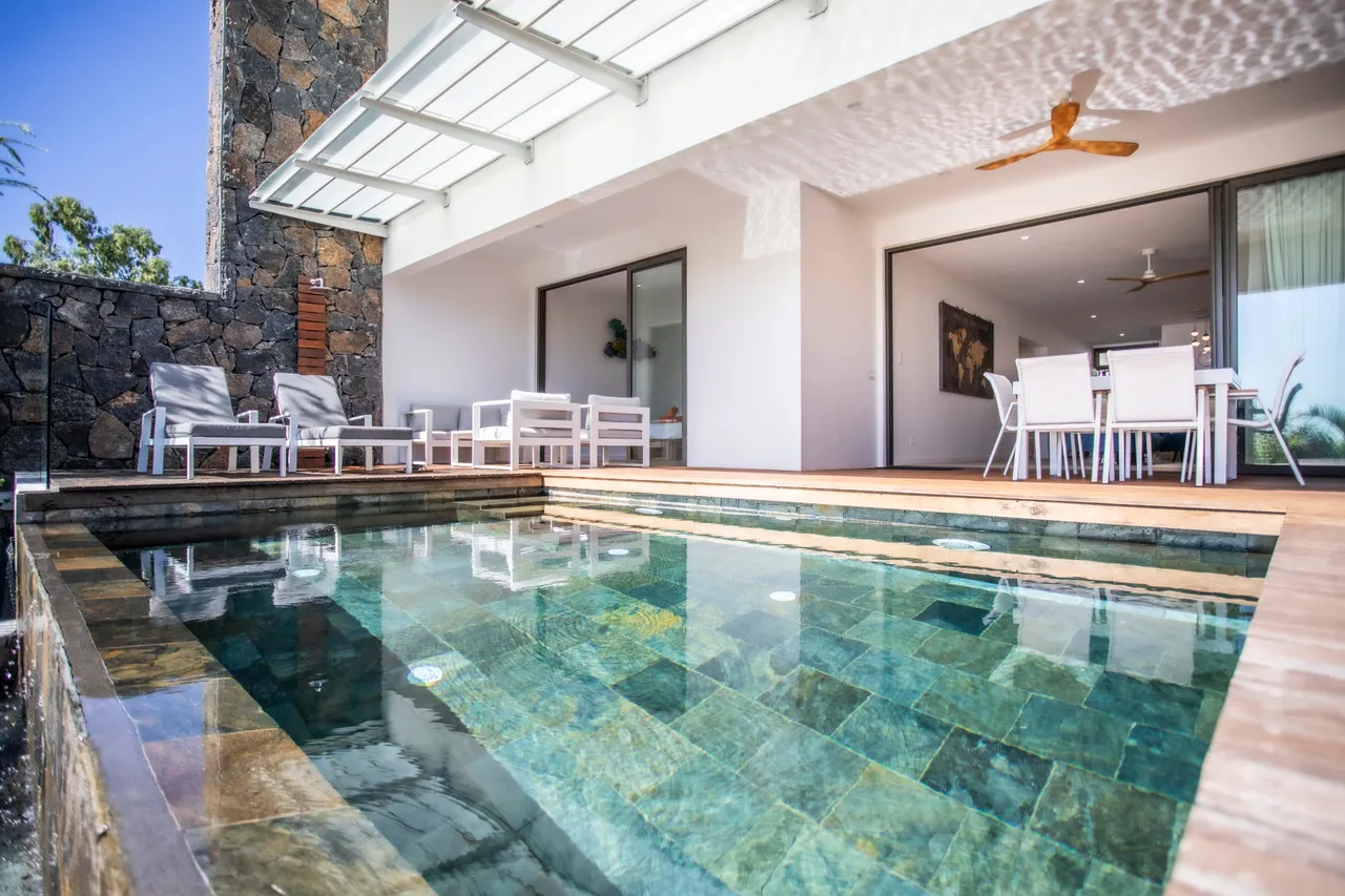 Terrasse avec piscine et chaises longues. Accès au salon et à la salle à manger.