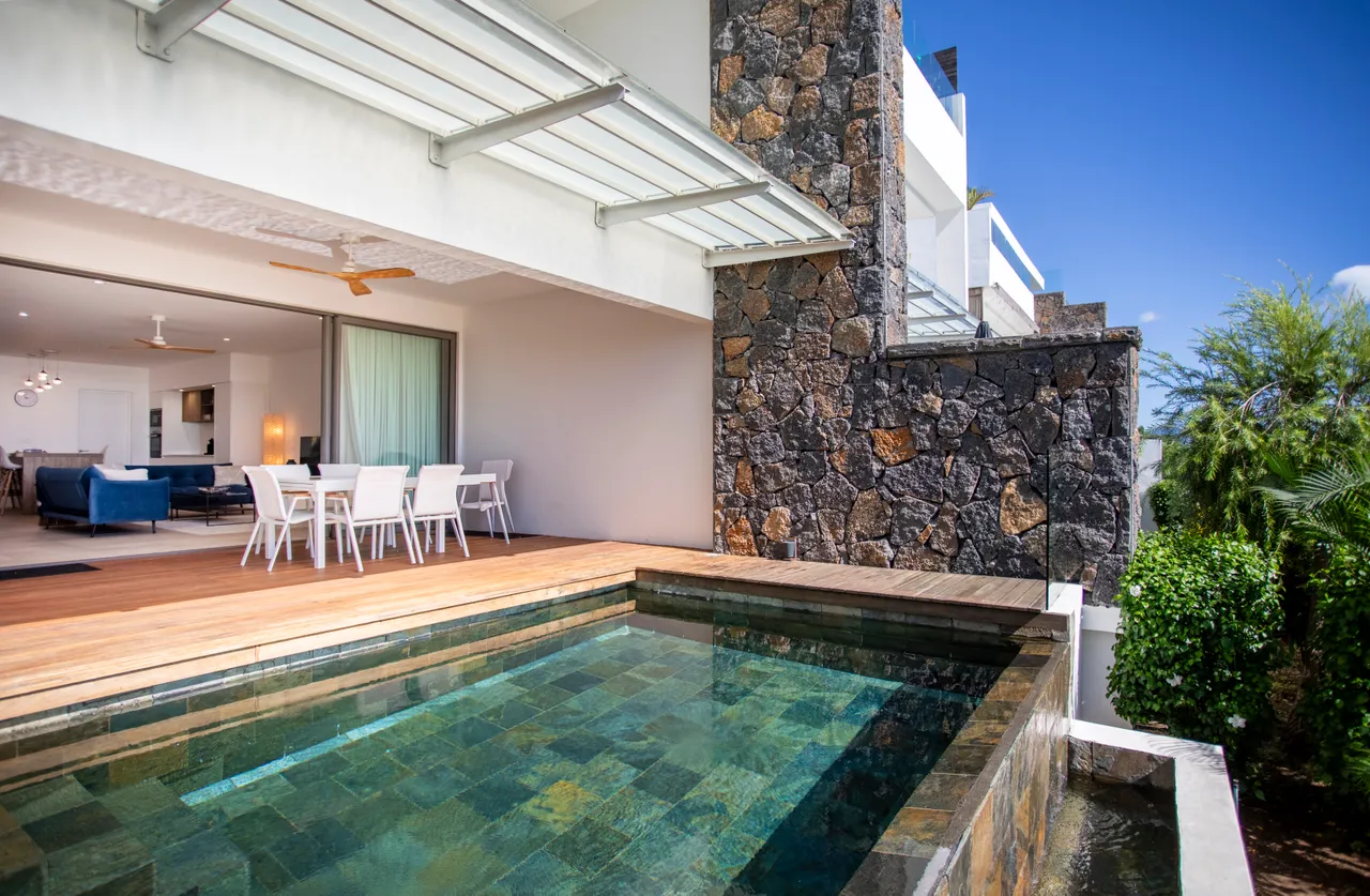 Terrasse en bois avec piscine et chaises blanches. Vue sur la mer.
