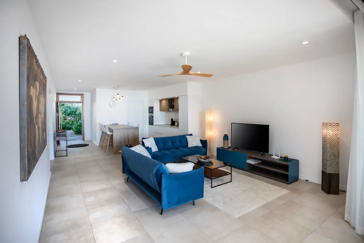 Espace de vie avec sol en carrelage et mobilier moderne. Accès à la cuisine.