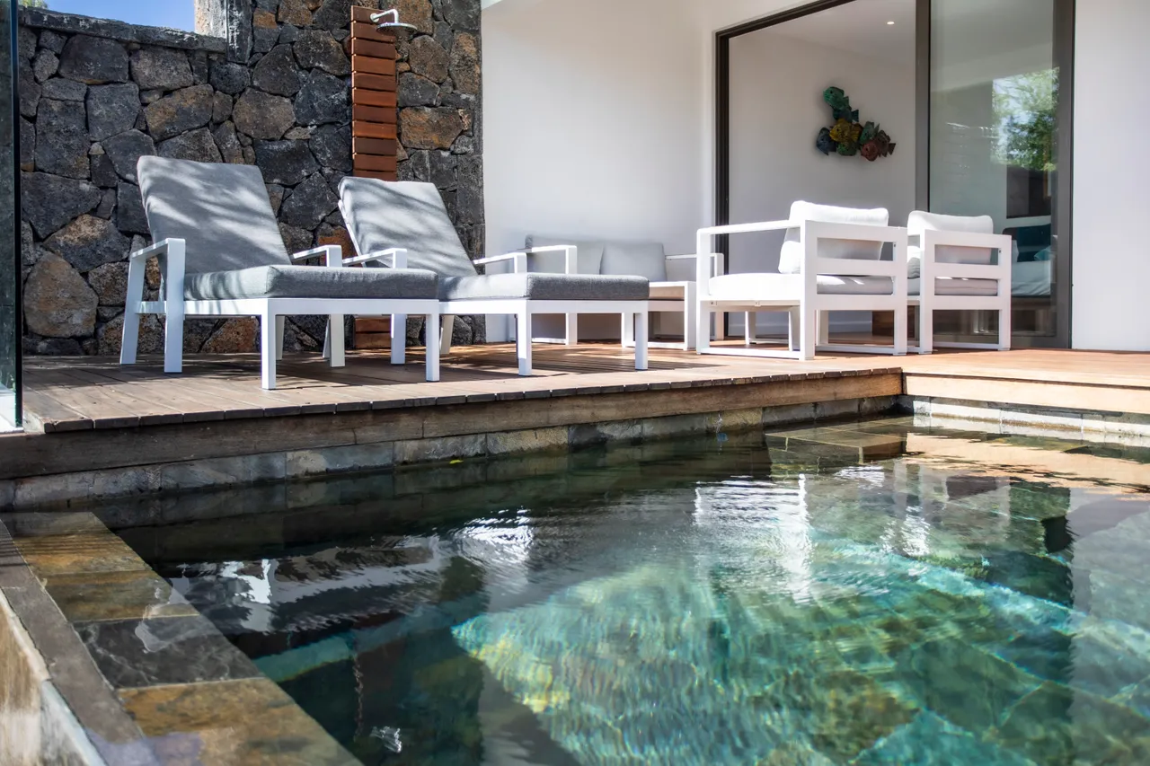 Espace extérieur avec canapés et vue directe sur la piscine. Accès à la mer.
