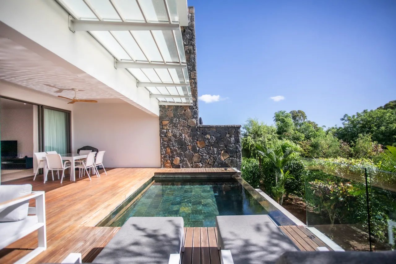 Espace extérieur avec piscine et chaises longues. Vue sur la végétation environnante.