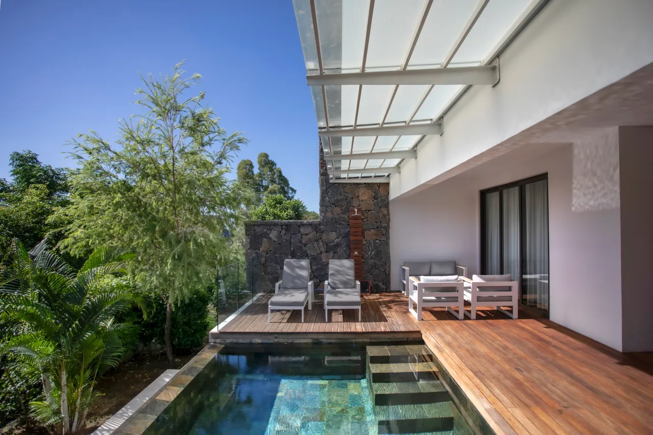 Espace de détente avec chaises longues. Vue sur la piscine et la verdure.