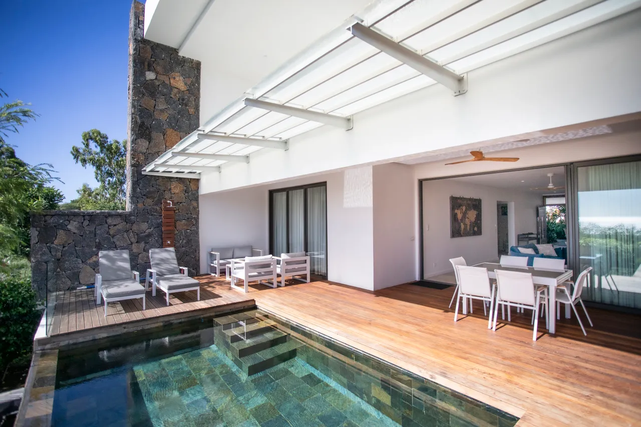 Terrasse en bois avec piscine et mobilier en blanc. Vue sur la mer.