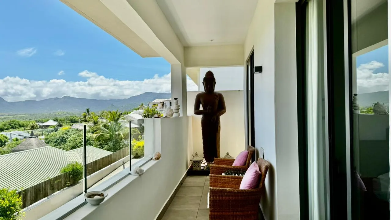 Terrasse avec chaises en rotin et statue décorative. Vue sur les montagnes.