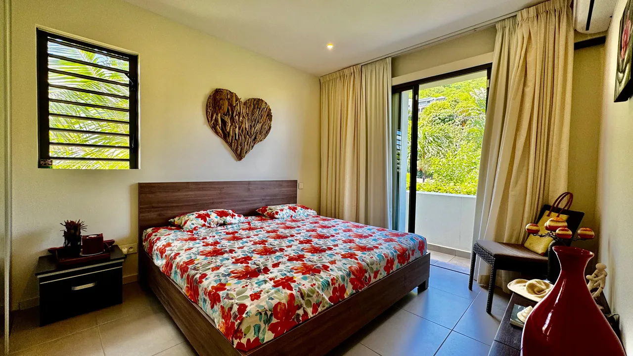 Chambre avec un lit double et accès à un balcon. Décoration florale sur la literie.