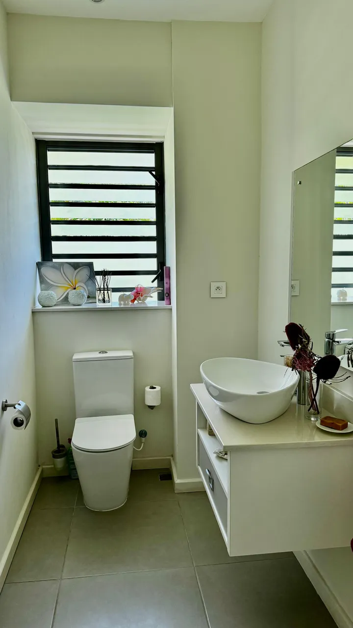 Salle de bain moderne avec carrelage gris et meuble de rangement intégré.