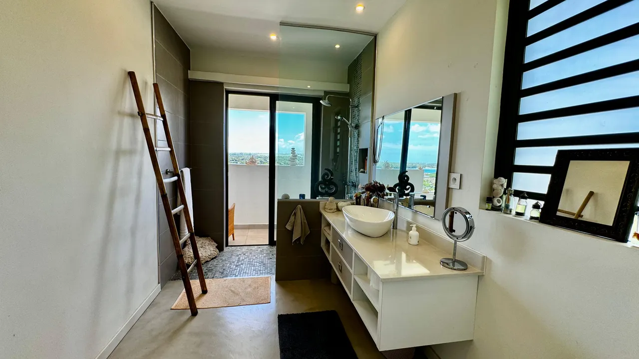 Mur blanc dominant dans une salle de bain avec douche à l'italienne. Meuble vasque sous éclairage naturel.
