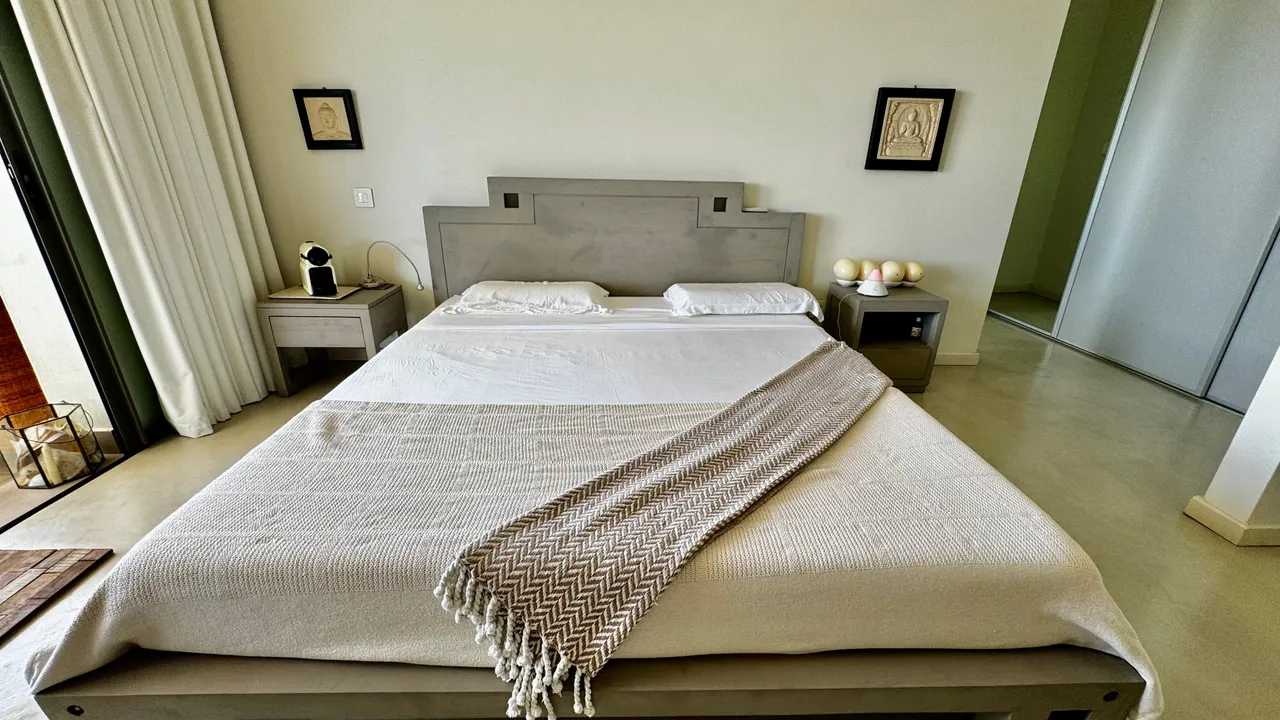 Chambre spacieuse avec un lit double et accès direct à une terrasse. Mur en teintes neutres et mobilier contemporain.