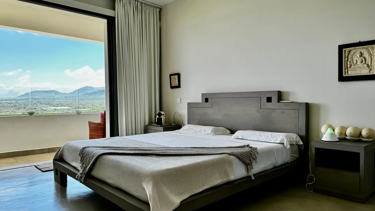 Chambre avec sol en carrelage et lit double au design épuré. Vue sur la mer depuis la fenêtre.