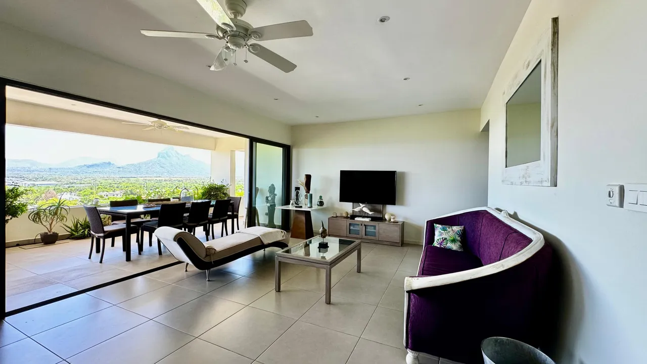 Sol en carrelage clair dans un salon spacieux avec des baies vitrées. Mobilier contemporain et accès direct à une terrasse.