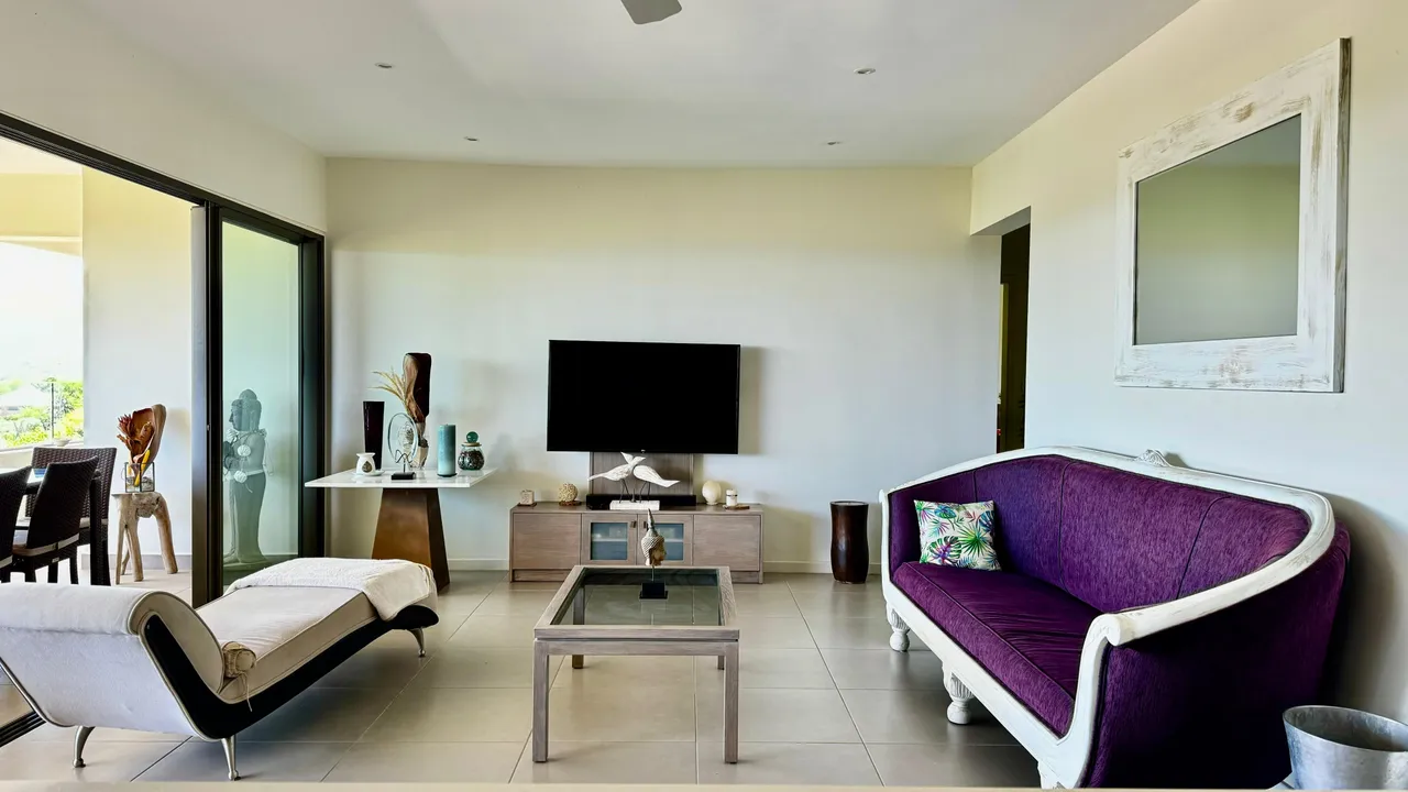 Tons neutres dans un salon spacieux avec une grande baie vitrée. Mobilier contemporain comprenant un canapé en velours.