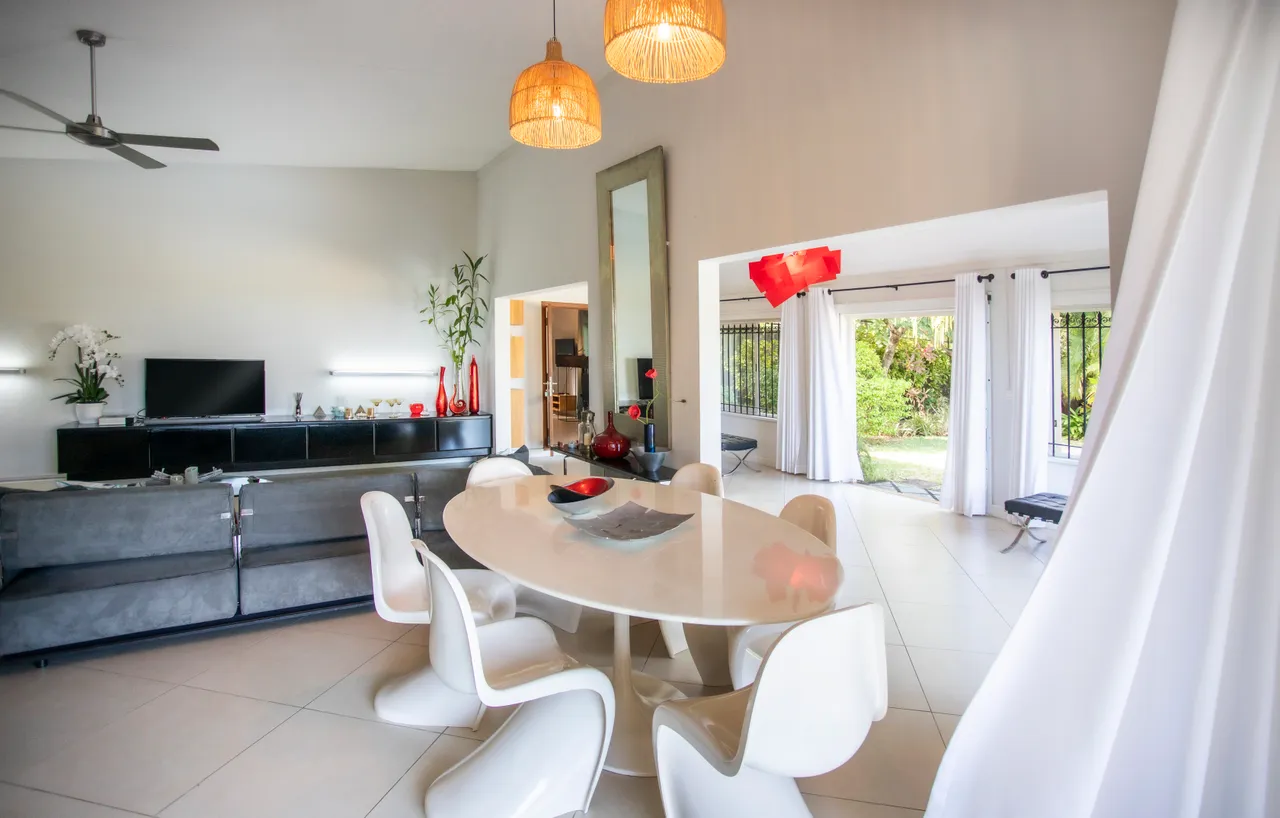 Espace de la galerie avec mobilier moderne et vue sur le jardin.  
Grandes baies vitrées apportent une luminosité naturelle à l'intérieur.  
Les couleurs neutres créent une atmosphère apaisante et contemporaine.  
Coin repas spacieux avec table ovale et chaises design.  
L'agencement open space facilite les échanges entre les pièces.