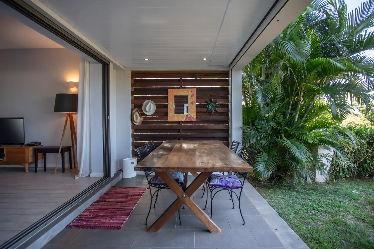 Terrasse charmante avec vue sur jardin tropical et espace convivial.