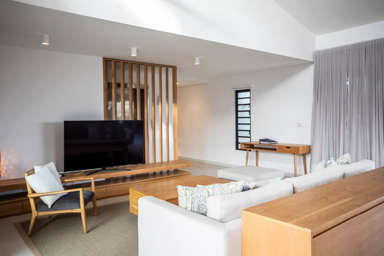 Espace de vie lumineux avec télévision montée sur un mur en bois.  

Mobilier épuré en bois et tissu créant une atmosphère contemporaine.  

Espace d'étude avec vue sur l'extérieur.  

Éclairage discret intégrant une touche moderne à l'intérieur.  

Séparation en bois ajoutant un élément architectural à la pièce.