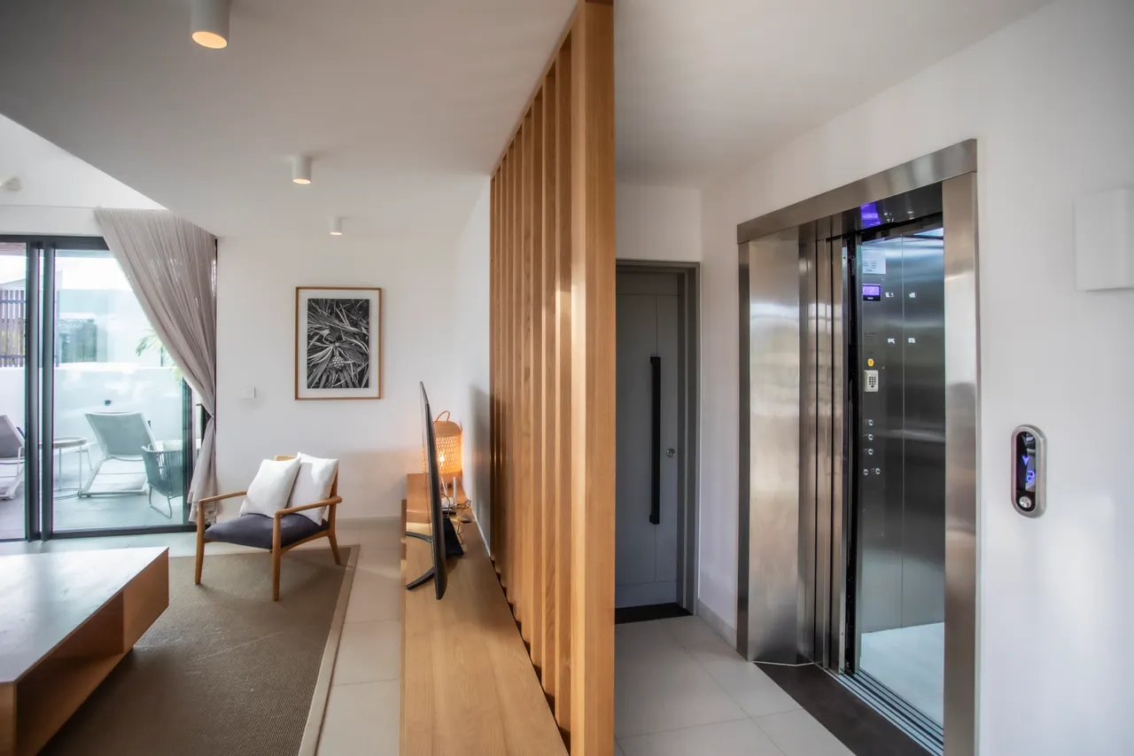 Galerie spacieuse avec éclairage intégré et circulation fluide entre les espaces.  
Mur en bois ajoutant une dimension chaleureuse à l'entrée.  
Accès direct à la terrasse depuis le séjour, favorisant la lumière naturelle.  
Éléments contemporains soulignant le design moderne de l'intérieur.  
Mobilier épuré et discret créant une atmosphère accueillante.