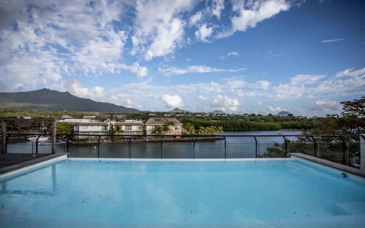 Vue panoramique sur la rivière et les collines depuis la terrasse.  

Piscine avec eau claire offrant un espace de détente.  

Terrasse bordée de verre pour une vue dégagée sur l'environnement.  

Mobilier extérieur moderne permettant de profiter de l'espace.  

Ciel dégagé créant une ambiance lumineuse et ouverte.