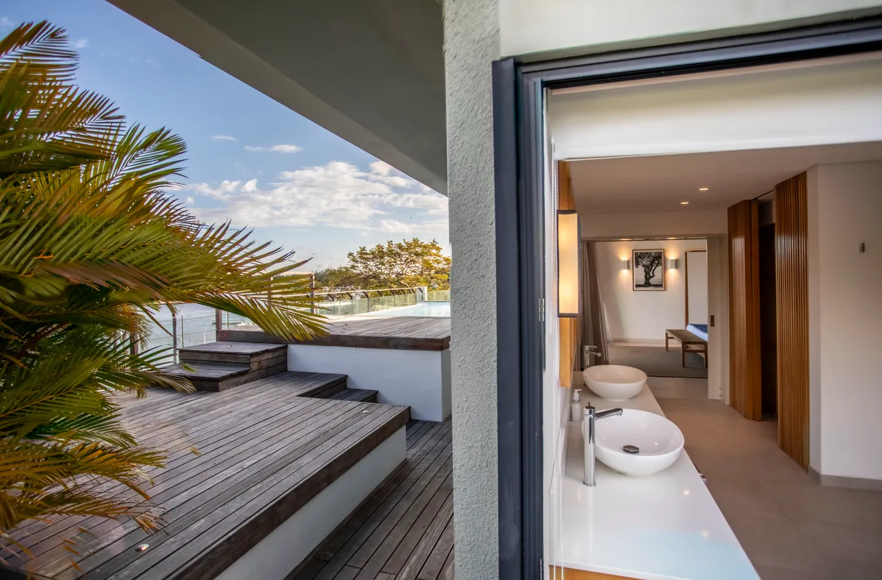 Salle de bain moderne avec double vasque et miroir minimaliste. 

Accès direct à la terrasse pour profiter de l'extérieur. 

Fenêtre large apportant lumière naturelle et vue sur le paysage. 

Robinetterie contemporaine ajoutant une touche design à l'espace. 

Terrasse en bois offrant un espace extérieur pour se détendre.