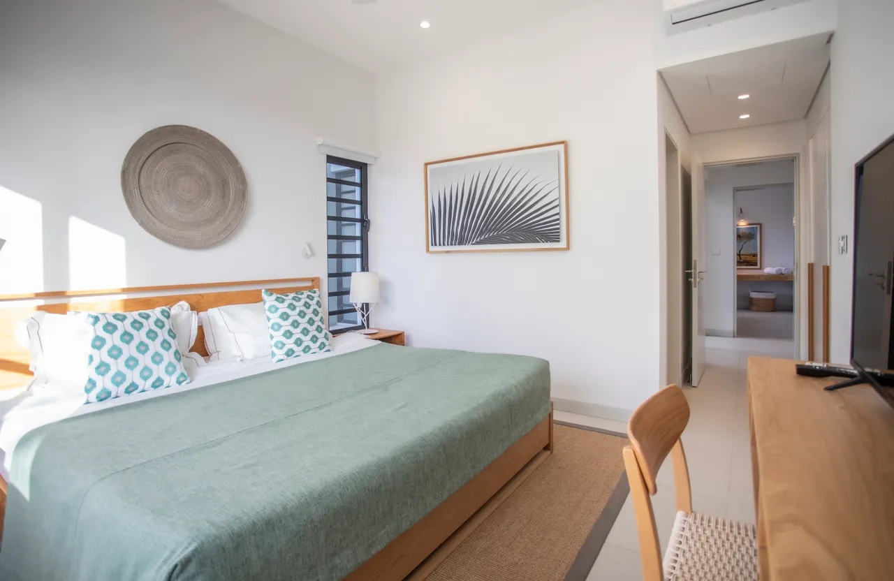 Chambre avec lit double et textile en lin pour un confort optimal. 

Espace de travail minimaliste avec bureau en bois et chaise élégante. 

Fenêtre large permettant une belle luminosité et vue sur l'extérieur. 

Tons neutres des murs créant une atmosphère apaisante. 

Rangement intégré offrant une solution pratique pour l'organisation des affaires.