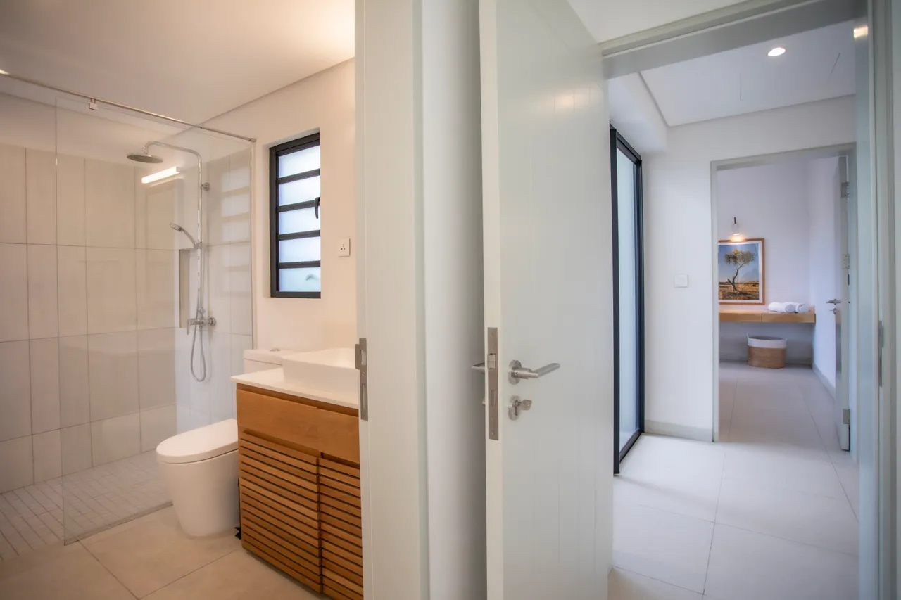 Salle de bain contemporaine avec mobilier en bois et douche à l'italienne. 

Vitrine épurée laissant entrer la lumière naturelle dans l'espace. 

Éclairage intégré soulignant les lignes modernes du décor. 

Rangement fonctionnel offrant une solution pratique pour les accessoires. 

Carrelage clair apportant une ambiance lumineuse et aérée.