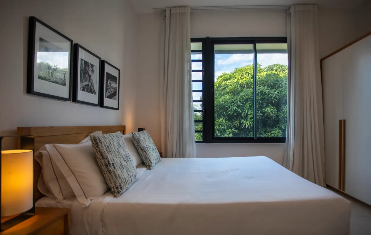 Chambre avec lit double et décor minimaliste pour un style épuré. 

Fenêtre large offrant une vue sur la végétation environnante. 

Éclairage doux créant une ambiance sereine dans l'espace. 

Rangement intégré optimisant l'utilisation de la pièce. 

Textiles en lin ajoutant une touche de confort au mobilier.