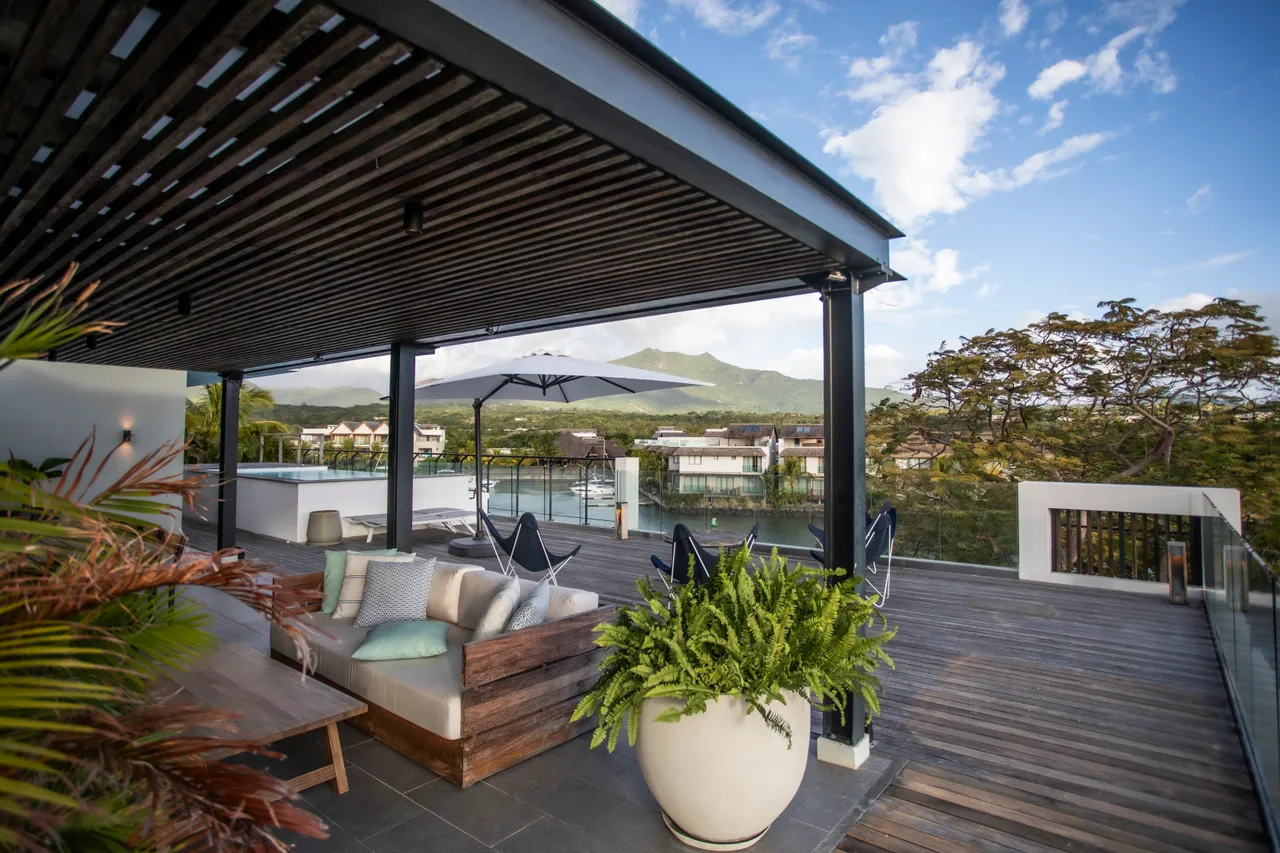 Espace extérieur avec sièges confortables et vue sur la nature environnante. 

Plafond en bois ajoutant une touche chaleureuse à l'aménagement. 

Mobilier moderne en bois favorisant des moments de détente. 

Parasols offrant de l'ombre pour profiter des journées ensoleillées. 

Terrasse spacieuse intégrant une ambiance accueillante et relaxante.