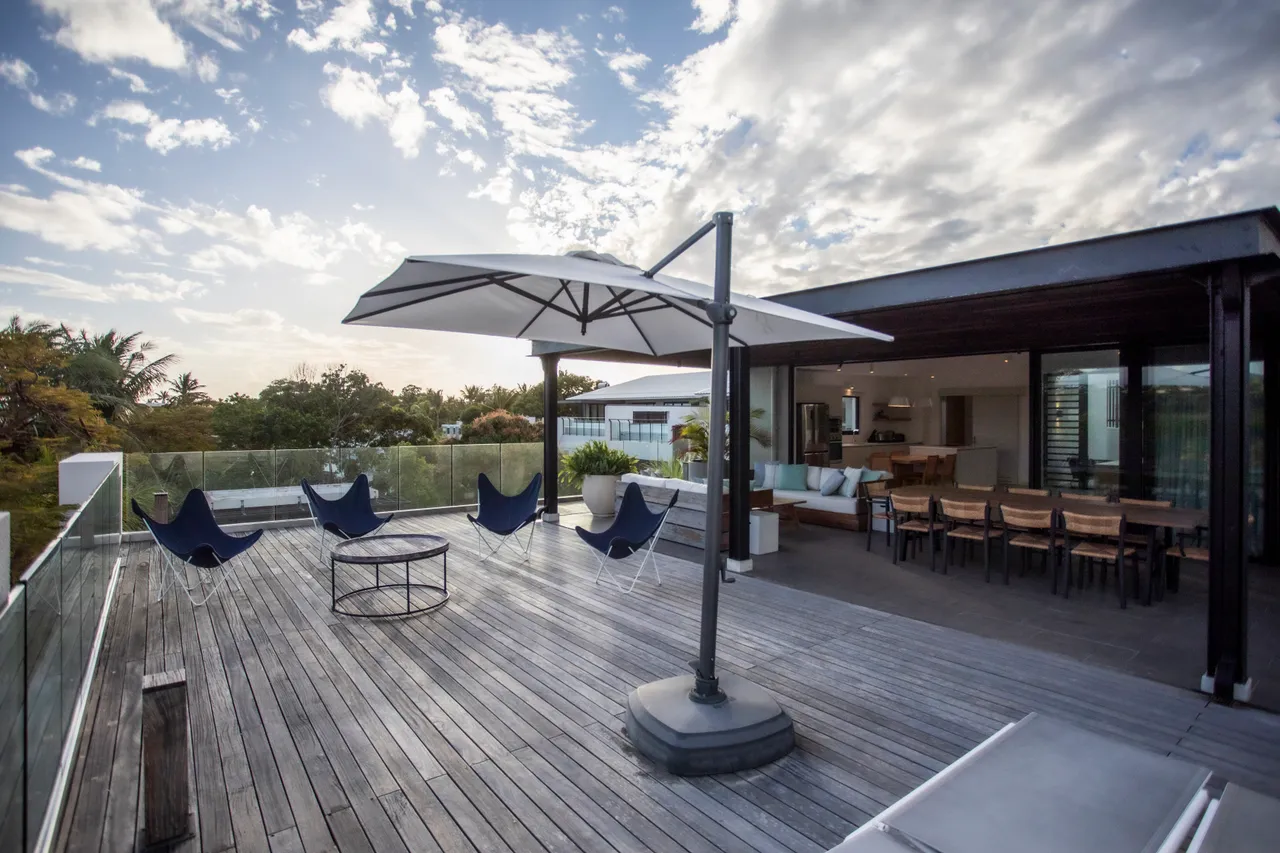 Espace extérieur avec fauteuils confortables et table basse centrale. 

Parasol offrant de l'ombre pour profiter des journées ensoleillées. 

Terrasse en bois favorisant une ambiance conviviale et détendue. 

Vue dégagée sur la nature environnante ajoutant une dimension paisible. 

Mobilier en bois créant une atmosphère chaleureuse et accueillante.