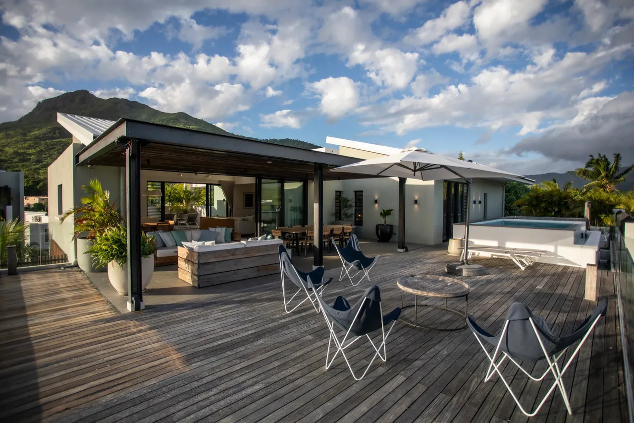 Espace extérieur en bois avec vue dégagée sur les montagnes. 

Mobilier d'extérieur moderne favorisant la détente et le confort. 

Parasols positionnés pour assurer de l'ombre au besoin. 

Zone de repas extérieure intégrant une grande table en bois. 

Chaises longues disposées près de la piscine pour se relaxer.