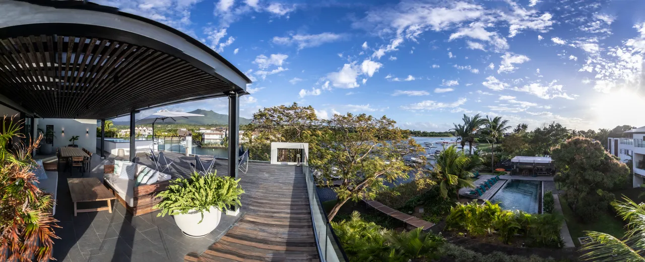 Espace extérieur avec vue panoramique sur la végétation environnante. 

Terrasse en bois offrant un accès direct à la piscine. 

Mobilier en bois agencé pour favoriser des moments de convivialité. 

Parasols disposés pour ombrager les assises en plein air. 

Zone de détente avec fauteuils confortables pour profiter des journées.