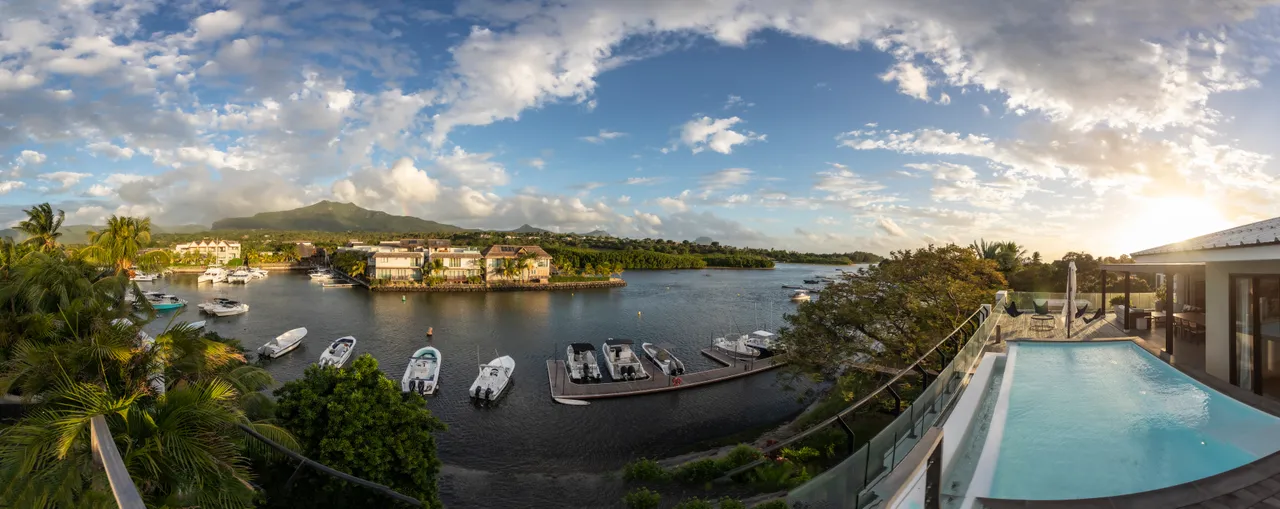 Espace de vie avec baies vitrées offrant une vue sur le port. 

Terrasse spacieuse équipée d'une piscine et de chaises longues. 

Végétation environnante créant une atmosphère intime et naturelle. 

Mobilier moderne et fonctionnel pour le confort extérieur. 

Lumière naturelle inondant l'espace grâce aux grandes ouvertures.