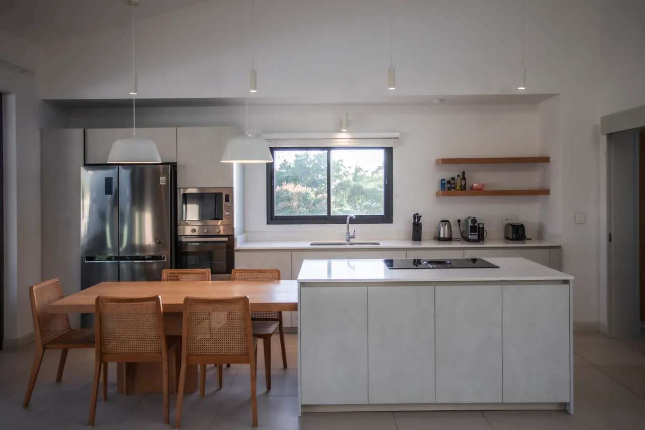 Cuisine moderne équipée d'appareils électroménagers en inox et de rangements fonctionnels. 

Table à manger en bois avec chaises tressées pour des repas conviviaux. 

Plan de travail spacieux offrant un espace de préparation optimal. 

Fenêtre donnant sur la verdure environnante pour une ambiance agréable. 

Éclairage suspendu apportant une touche contemporaine à l