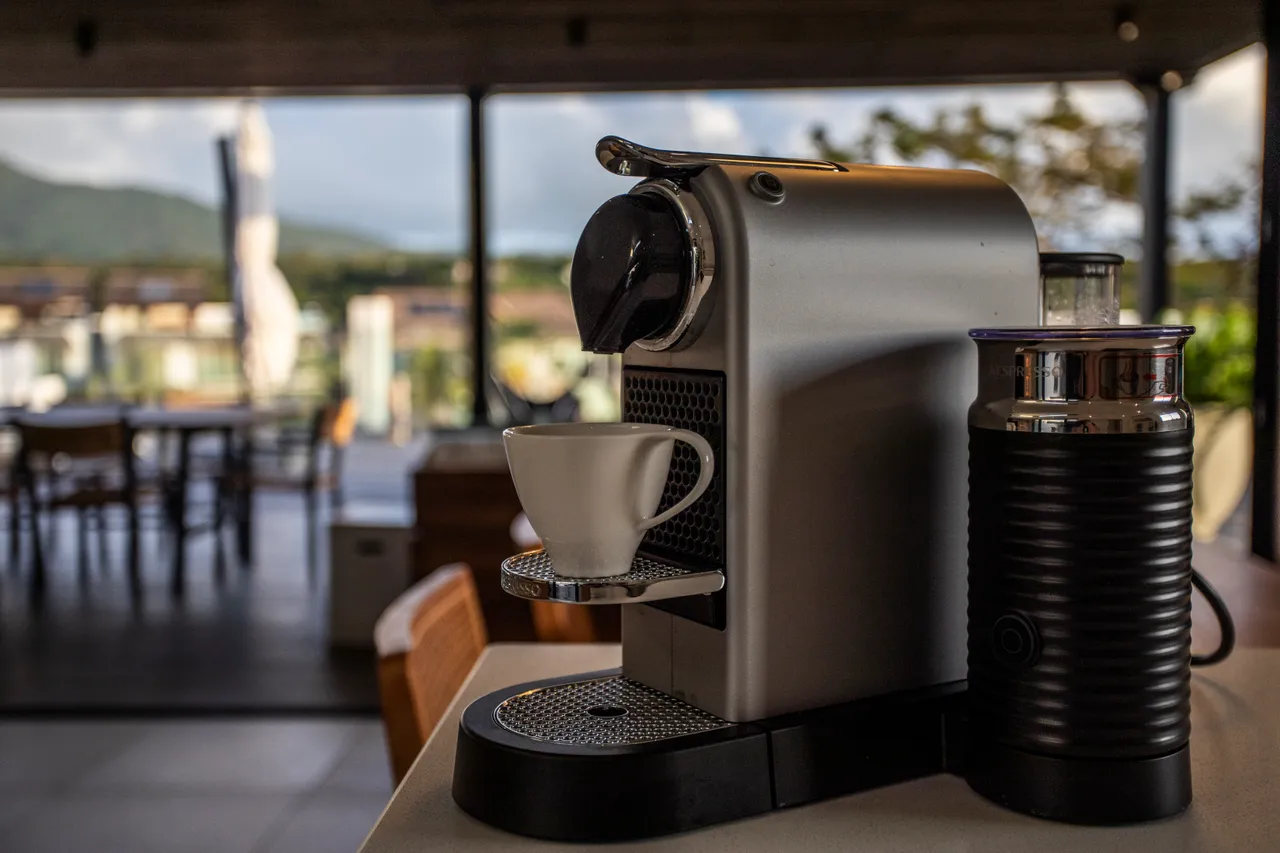 Espace de cuisine avec machine à café moderne et coin repas à proximité. 

Équipements de cuisine contemporains offrant fonctionnalité et confort. 

Fenêtre laissant entrer la lumière naturelle et vue sur l'extérieur. 

Mobilier en bois clair ajoutant une ambiance chaleureuse à l'espace. 

Plan de travail spacieux pour les préparations culinaires.
