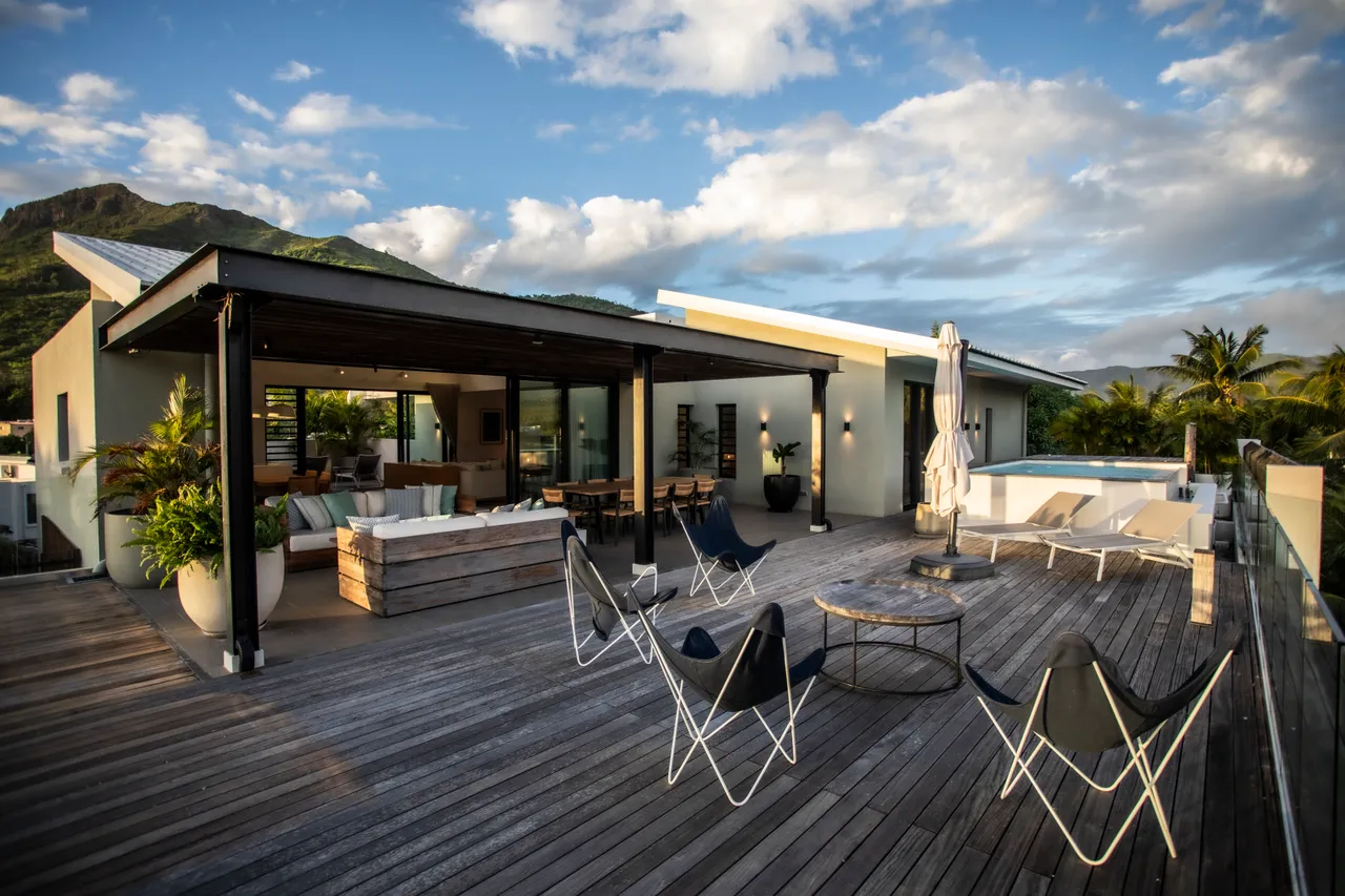 Terrasse en bois spacieuse avec mobilier moderne pour se détendre. 

Vue dégagée sur les montagnes environnantes depuis l'espace extérieur. 

Coin salon confortable à l'extérieur, propice aux rassemblements. 

Parasol offrant de l'ombre pour profiter du soleil. 

Accès direct à la piscine depuis la terrasse en bois.