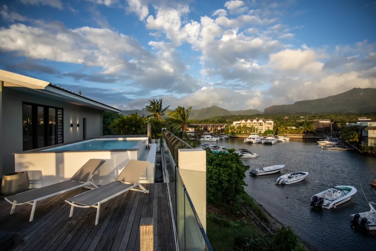 Terrasse avec piscine privée offrant une vue sur le port et les montagnes. 

Chaises longues en bois disposées pour profiter du soleil. 

Espace extérieur propice à la détente avec vue dégagée sur l'eau. 

Végétation environnante créant un cadre naturel et intime. 

Accès direct à la piscine depuis la terrasse pour un rafraîchissement immédiat.