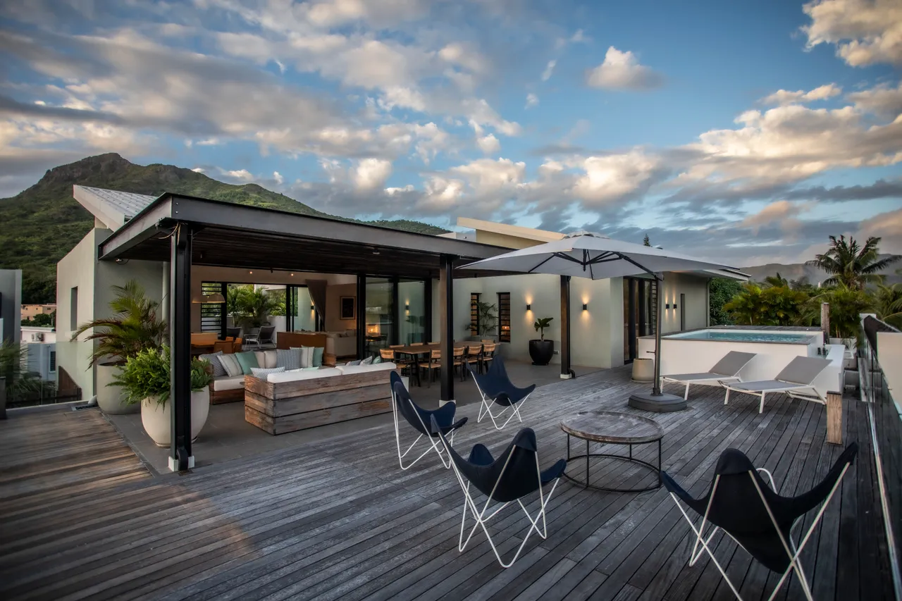 Espace extérieur offrant une vue dégagée sur les montagnes environnantes. 

Terrasse en bois avec mobilier contemporain pour des moments de détente. 

Parasol déployé pour créer de l'ombre lors des journées ensoleillées. 

Coin repas sur la terrasse pour des repas en plein air. 

Accès direct à la piscine depuis l'espace extérieur pour un rafraîchissement immédiat